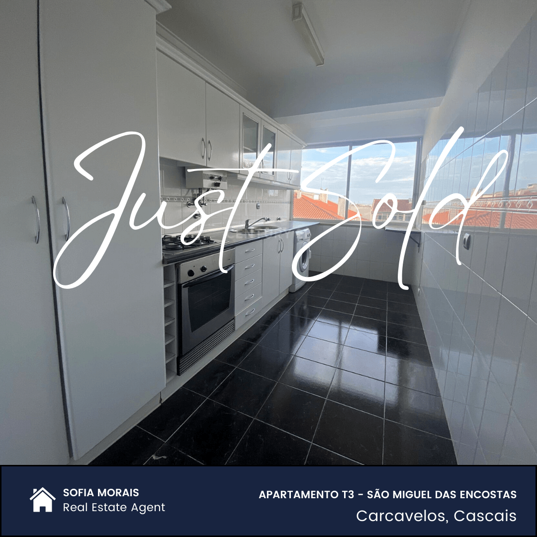 Modern white kitchen with black floor tiles and large window, overlaid text 'Just Sold.'